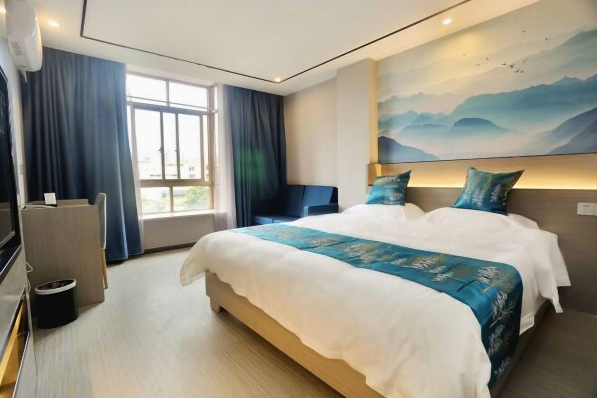 Ένα δωμάτιο ξενοδοχείου με ένα μεγάλο κρεβάτι, ένα γραφείο, μια καρέκλα και μια τηλεόραση.