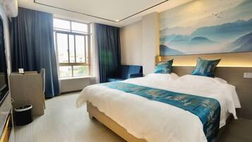 A hotel room with a large bed, a desk, a chair, and a TV.