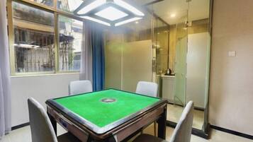 Een kamer met een pooltafel, een glazen scheidingswand en uitzicht op een gebouw.