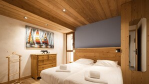 A bedroom with a wooden ceiling, a bed with white linens, a wooden dresser, a painting of sailboats, and a wooden wardrobe. - Chalet, view panoramic, terrace, fireplace or stove, parking, tv, ski locker, 168m², La Clusaz (La Clusaz)