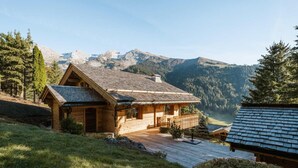 A wooden cabin with a sloped roof, a deck, and a view of a valley and mountains. - Chalet, view panoramic, terrace, fireplace or stove, parking, tv, ski locker, 168m², La Clusaz (La Clusaz)
