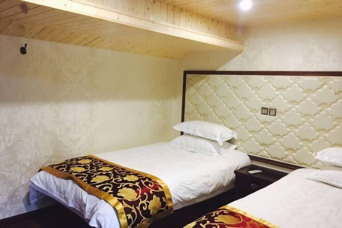 Una habitación con dos camas, cada una con cabecero y almohadas.