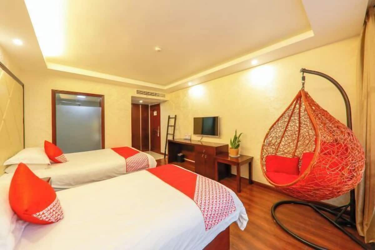 Una habitación de hotel con dos camas, un escritorio, un televisor y una silla colgante.