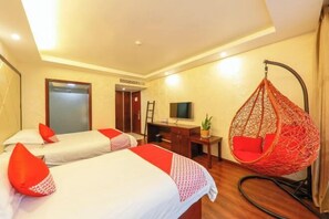 Una habitación de hotel con dos camas, un escritorio, un televisor y una silla colgante.