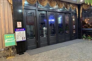 Entrada de hotel con puerta de vidrio, un cartel y piso de baldosas.