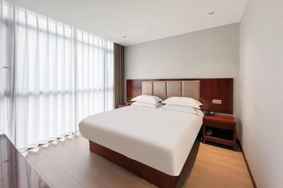 Ein Hotelzimmer mit einem großen Bett, einem Holzkopfteil und einem Nachttisch.