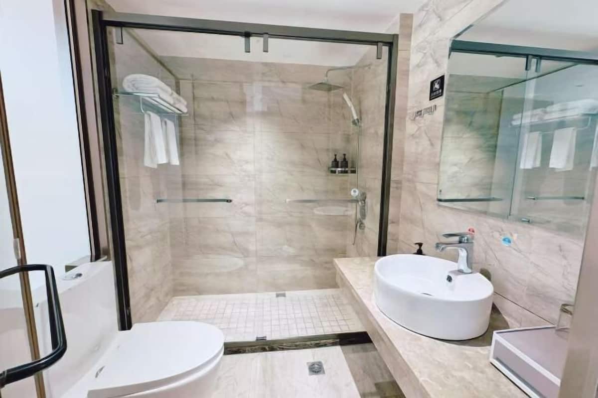 Ein modernes Badezimmer mit einer Duschkabine, einem weißen Waschbecken und einer Toilette.