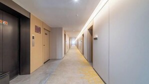 A long, narrow hallway with doors on both sides, leading to individual rooms.