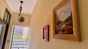 A hallway with a wooden door, a clock, and a painting of a mountainous landscape. - Appartement à 10min des Plages et Souks. Amis à 4 Pates Acceptés ! (Agadir)
