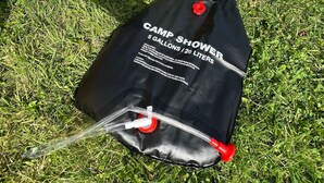 A black bag labeled "CAMP SHOWER 5 GALLONS / 20 LITERS" on grass. - Fossewold Camping Bell Tent 1 of 4 (Blockley)
