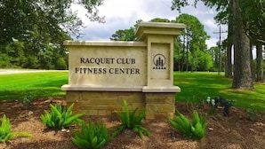 Señal para el Racquet Club Fitness Center, con base de piedra y un logo.