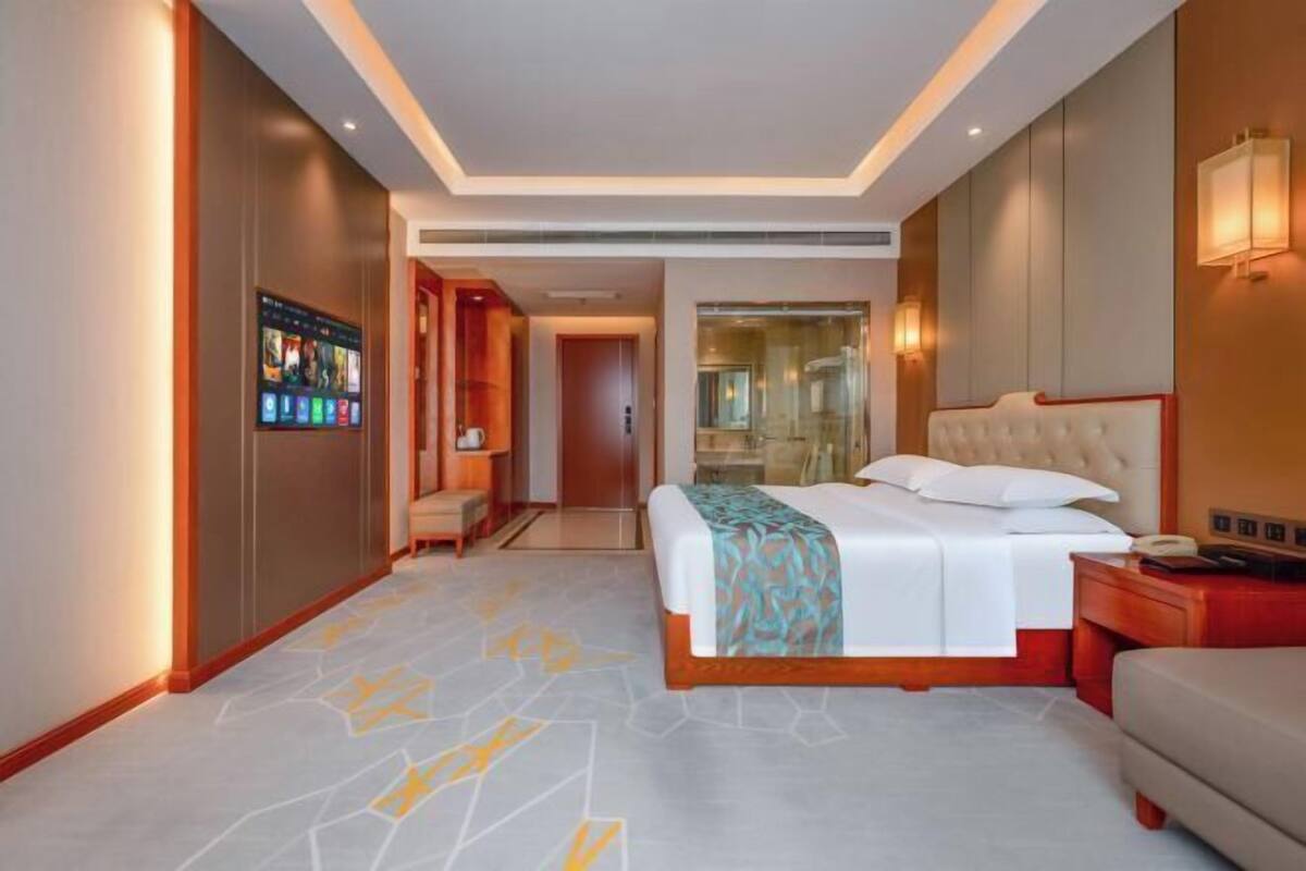 Ein Hotelzimmer mit Bett, Nachttisch und einem an der Wand befestigten Fernseher.