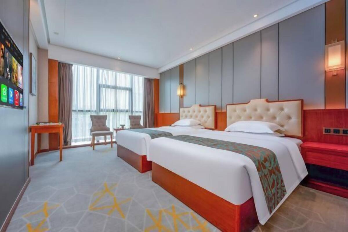 Ein Hotelzimmer mit einem großen Bett, einem Schreibtisch, einem Sessel und einem großen Fenster.