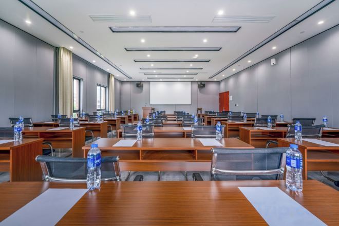 A conference room with multiple tables, chairs, and a projector screen.