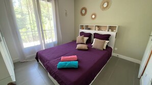 A bedroom with a large bed, a nightstand, a window with curtains, and wall decorations. - Le Mas de Fabregas. Chambre Dhôte Calme et Tranquille à 400m de la mer (La Seyne-sur-Mer)