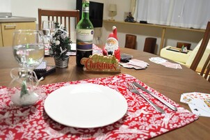 Uma mesa de jantar posta com um enfeite de Natal, uma garrafa e cartas de baralho.