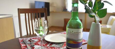 A dining table with a wine bottle, a glass of water, and a vase with roses.