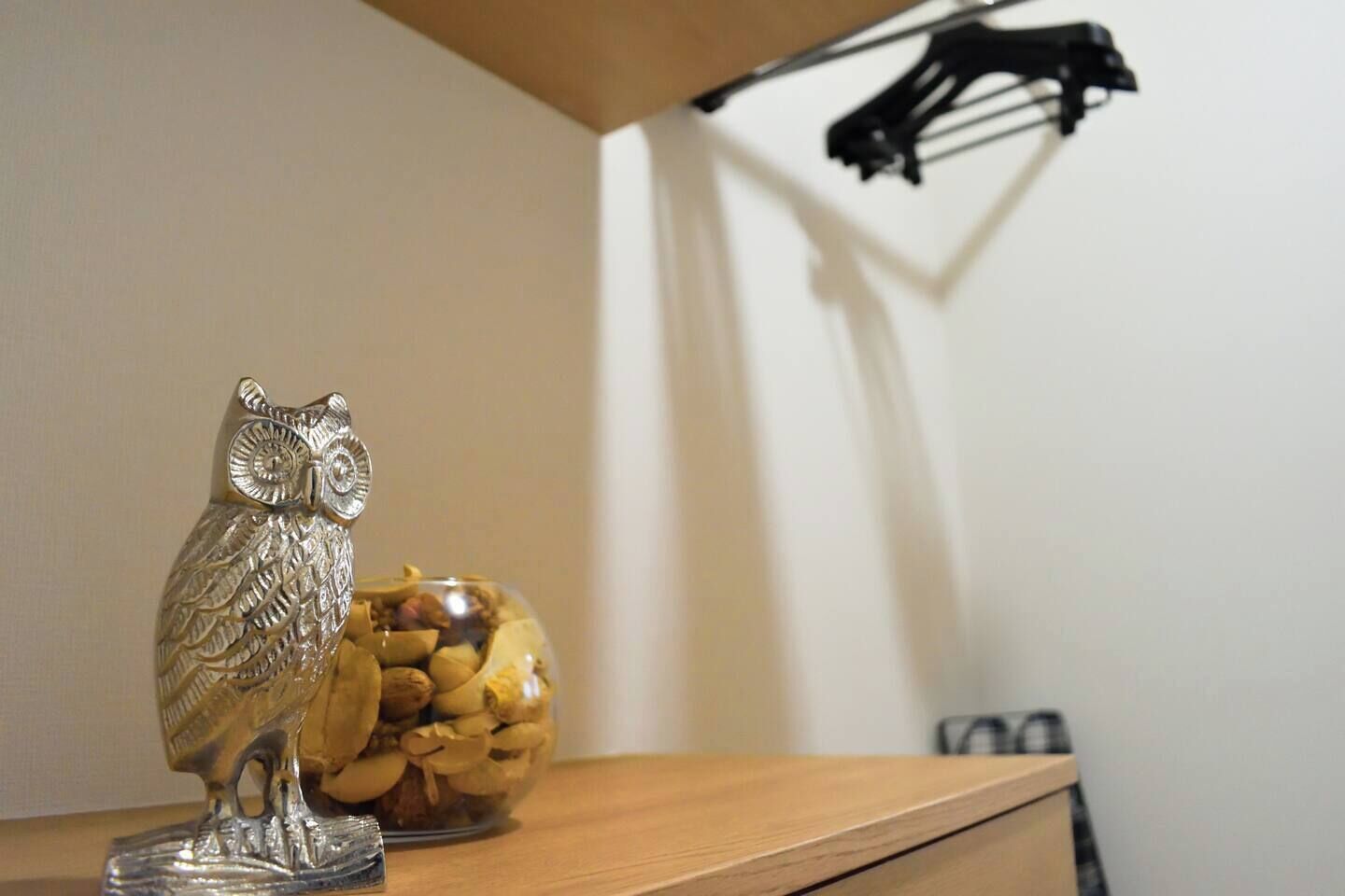 Una estantería de madera con una figura de un búho plateado y un cuenco de vidrio con nueces.