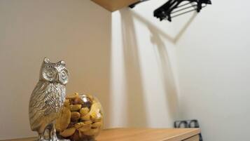 Una estantería de madera con una figura de un búho plateado y un cuenco de vidrio con nueces.