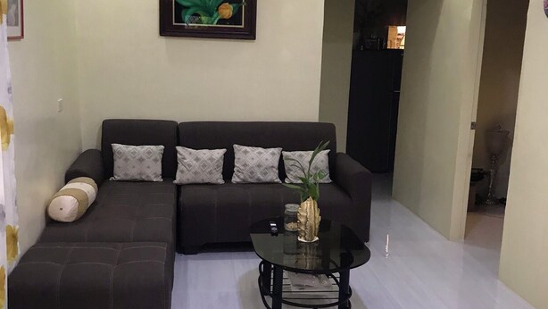 Una sala de estar con un sofá modular, una mesa de centro de vidrio y un cuadro con flores en la pared.