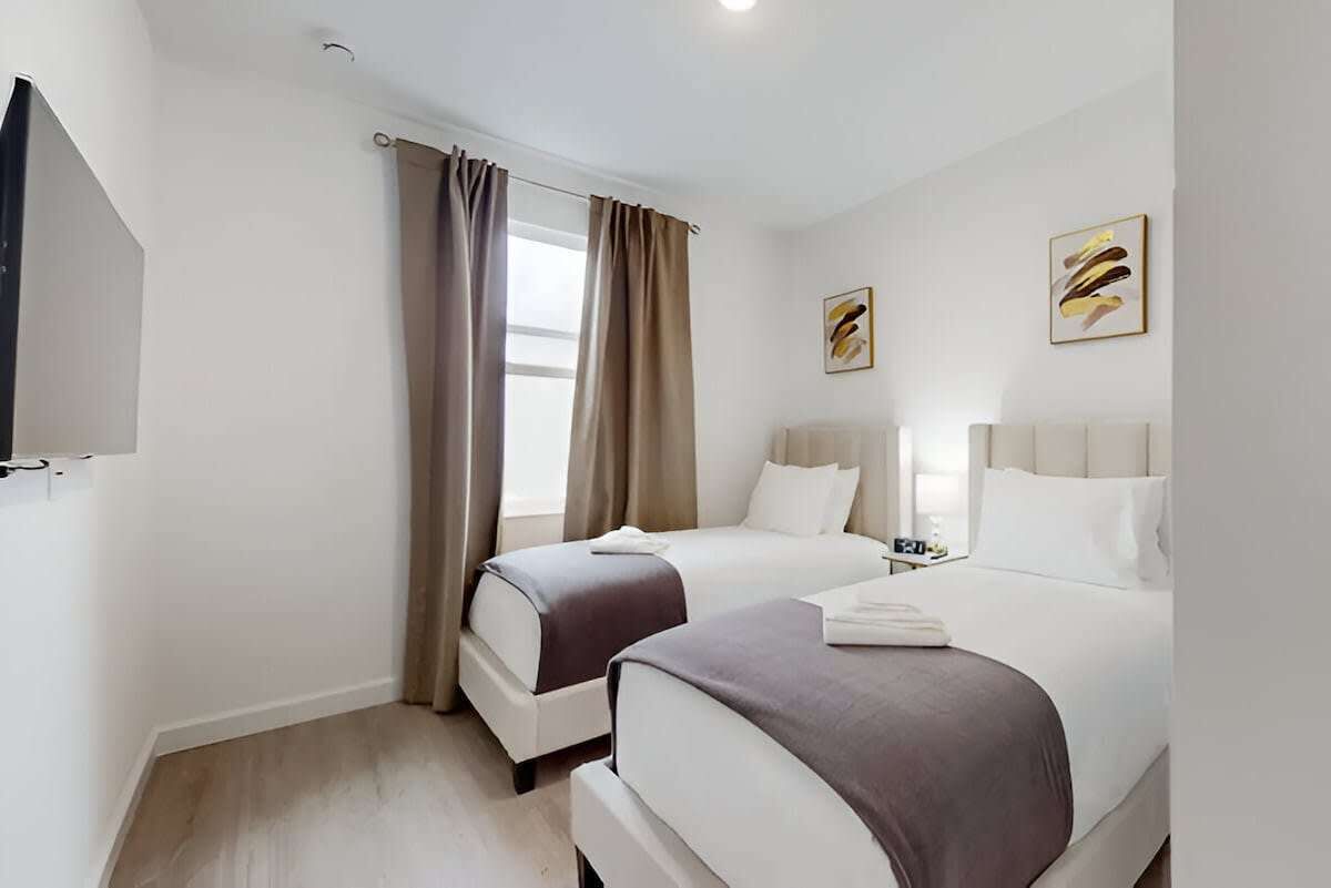 Une chambre d’hôtel avec deux lits, une télévision et des œuvres d’art accrochées aux murs.