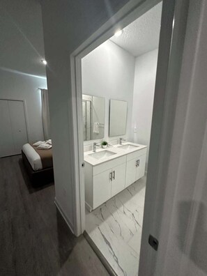 Une salle de bain moderne avec un double vasque, un grand miroir et un espace douche.