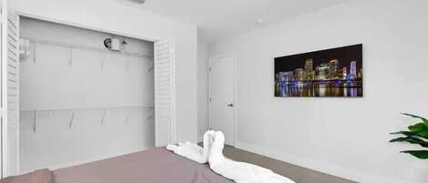 Ein Schlafzimmer mit einem Bett, einem weißen Kleiderschrank, einer Tür und einem Stadtbild an der Wand.