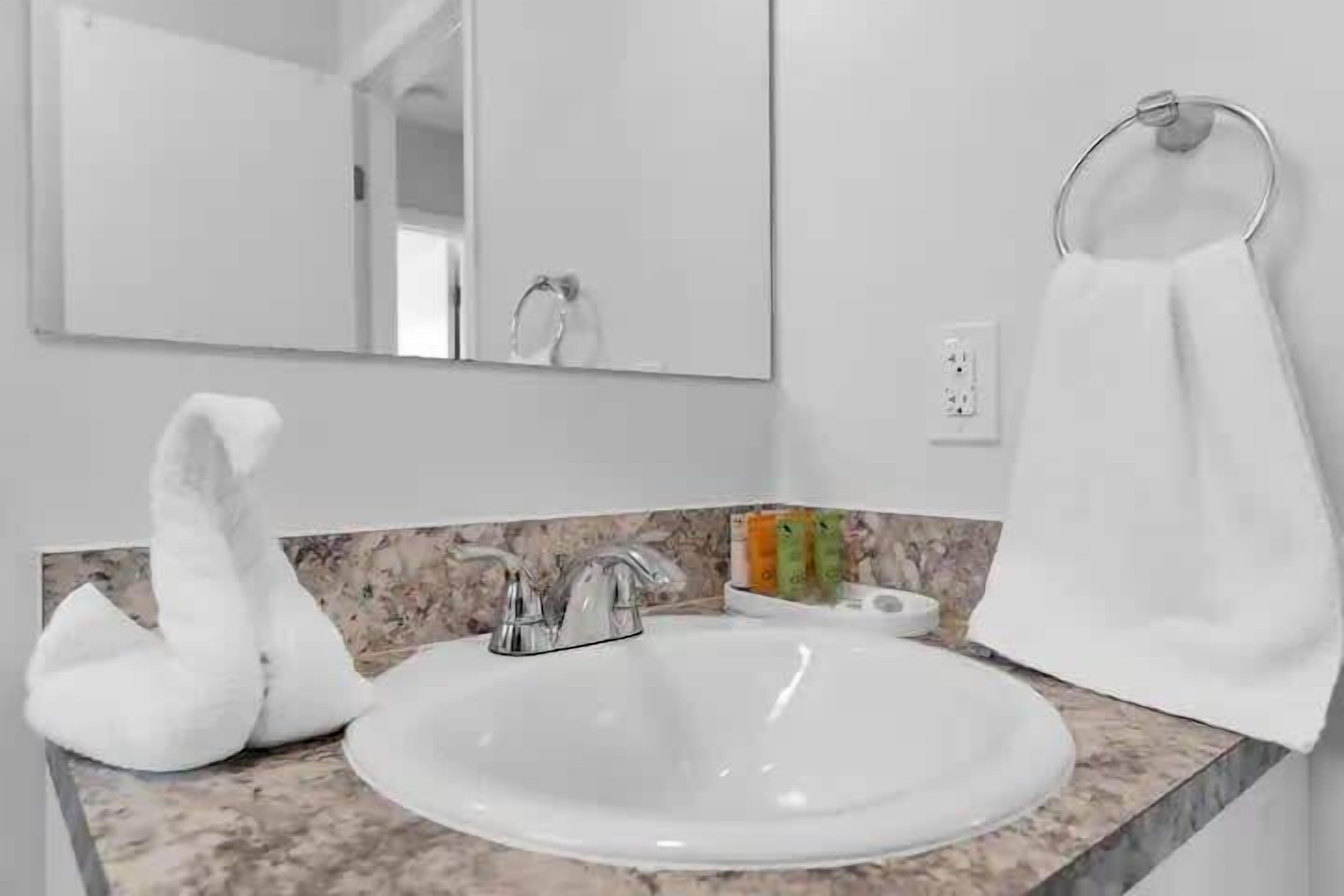 A bathroom with a white sink, a mirror, and a towel rack.