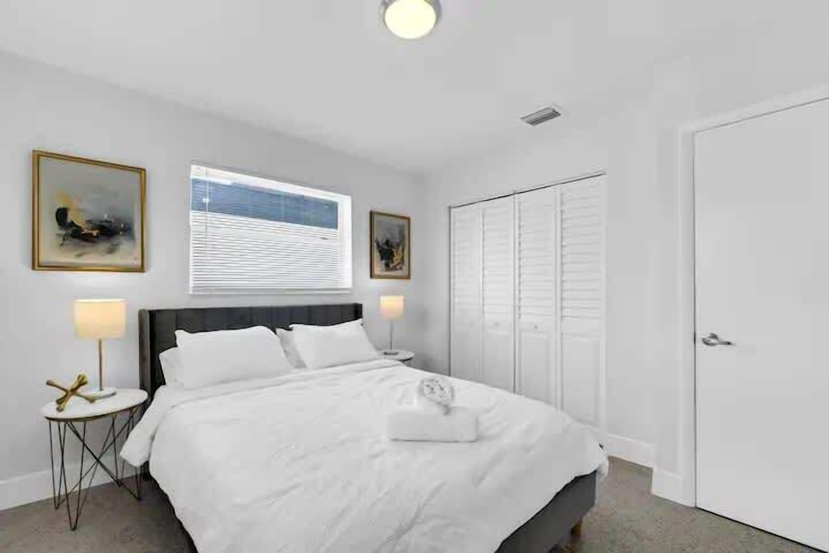 A neatly arranged bedroom with a bed, bedside tables, and a wardrobe.