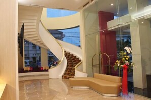 Un interior moderno con una escalera en espiral, una zona de estar y un jarrón con flores.