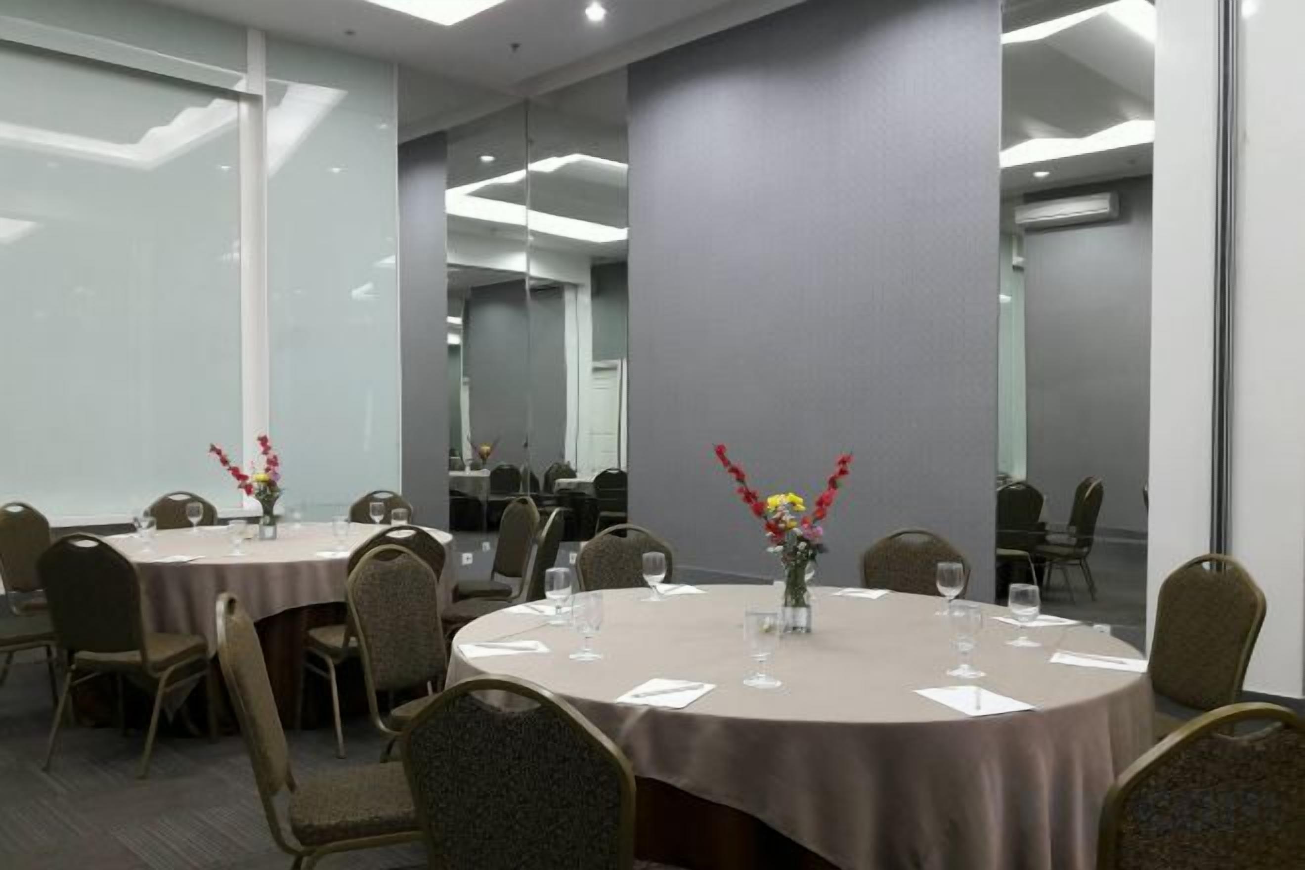 A conference room with round tables, chairs, and floral centerpieces.