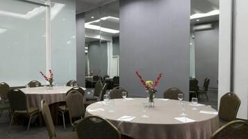 A conference room with round tables, chairs, and floral centerpieces.
