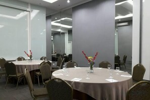 A conference room with round tables, chairs, and floral centerpieces. - Brits Hotel Puri Indah (West Jakarta)