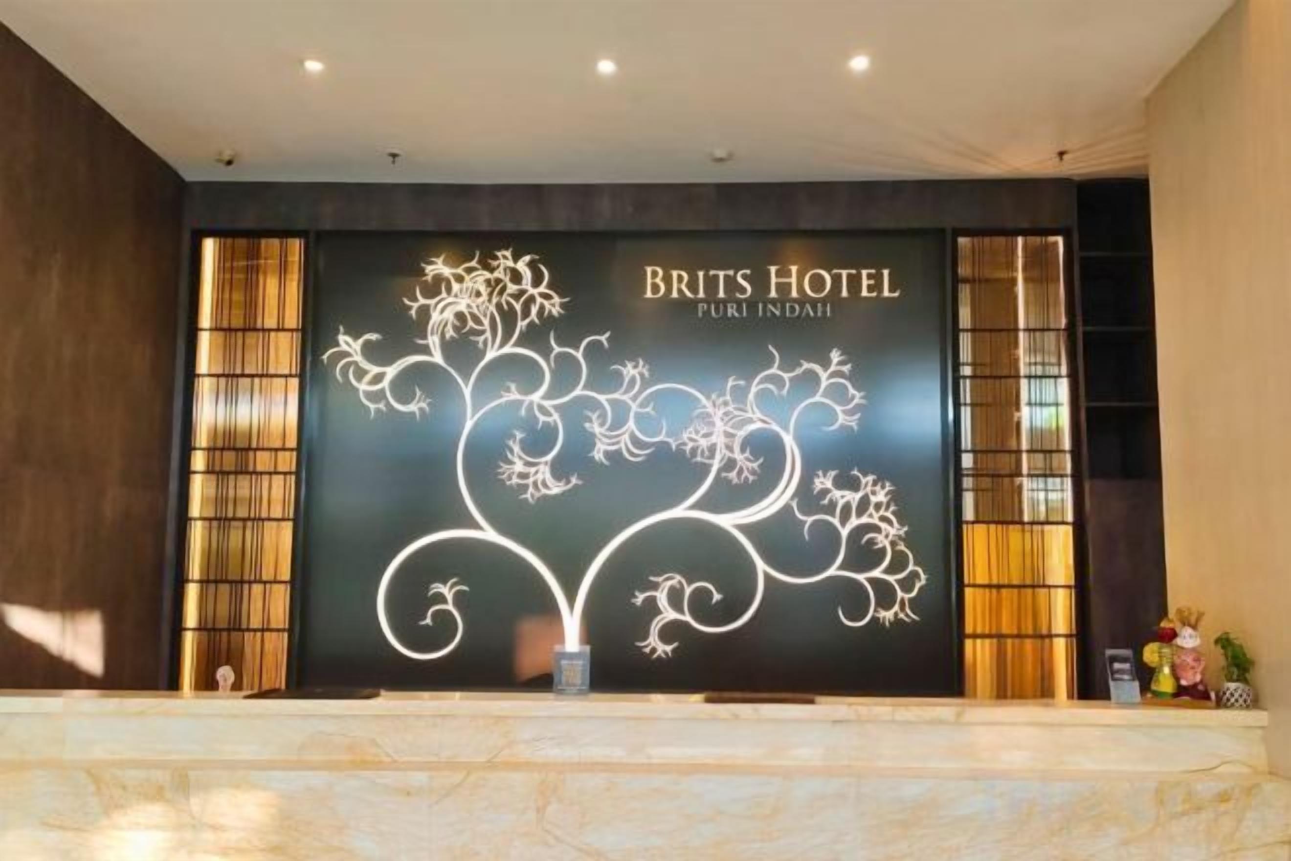 Moderne reception på Brits Hotel med et stort, oplyst skilt med hotellets navn.