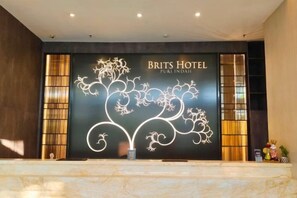 Una recepción en el Hotel Brits, con un diseño moderno, que presenta un gran letrero iluminado con el nombre del hotel.