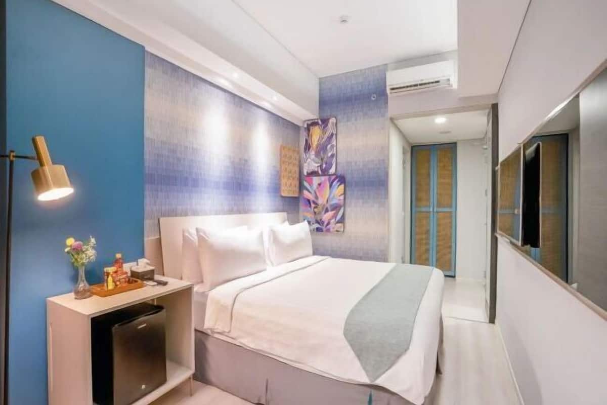 Een moderne hotelkamer met een bed, nachtkastje en televisie.