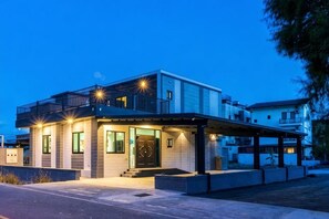 Una casa moderna de dos pisos con techo plano, un porche cubierto y una puerta principal.