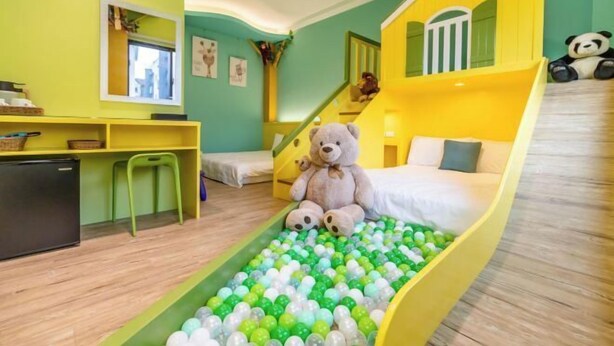 A room with a bed, a desk, a chair, a teddy bear, a ball pit, and a staircase. - Field Time Homestay (Yilan)