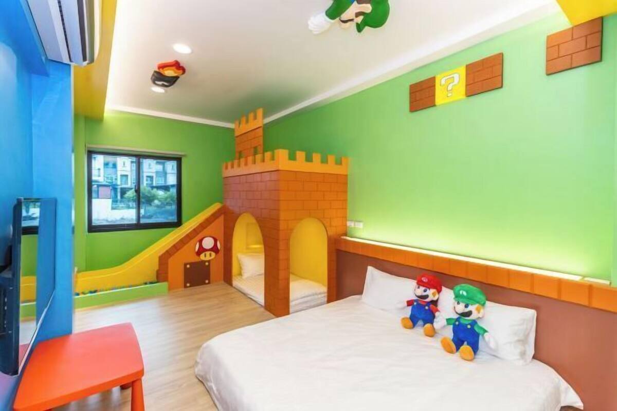 A children's room with a bed, Mario and Luigi plush toys, a slide, and a brick castle play structure.