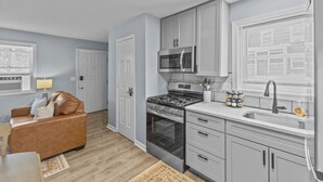 A compact kitchen with a gas stove, microwave, and stainless steel sink.