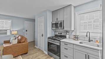 A compact kitchen with a gas stove, microwave, and stainless steel sink.