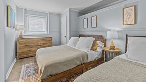 A bedroom with a bed, bedside tables, a dresser, and artwork on the walls.