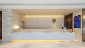 A modern reception area with a marble floor, a reception desk, a digital screen, and a wall-mounted sign. - JI Hotel (Xiamen Airport Huli Avenue) (Xiamen)