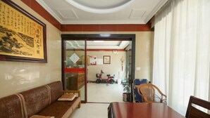 A room with a wooden dining table, a brown sofa, and a glass door leading to another area.