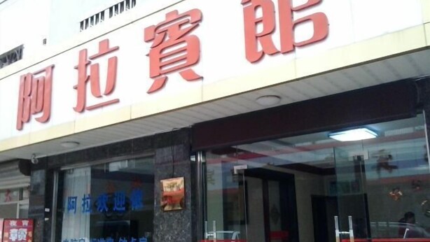 A hotel with a prominent red sign and a glass entrance.