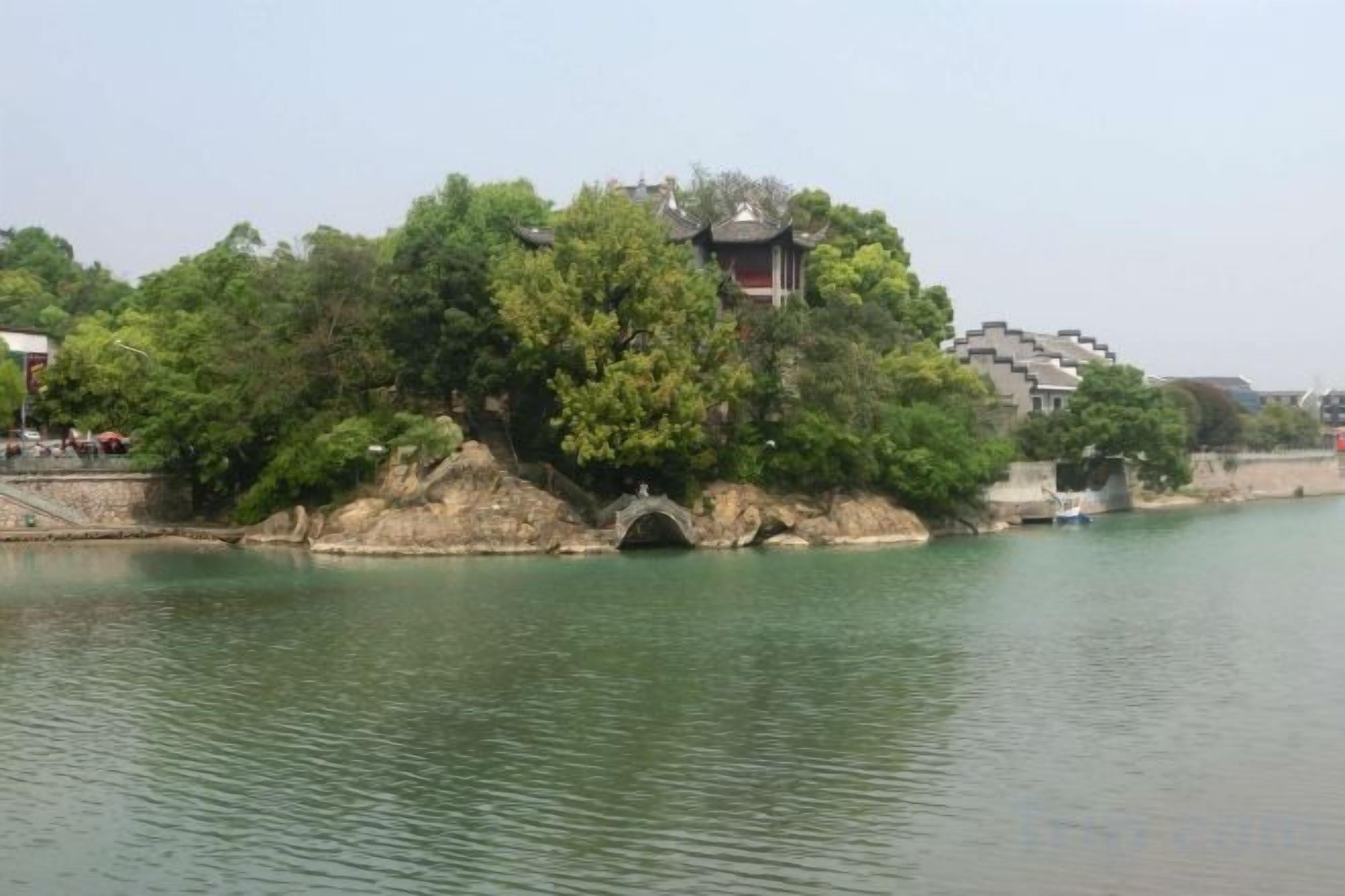 Un edificio tradicional con techo al estilo pagoda, ubicado en una isla rocosa rodeada de agua.