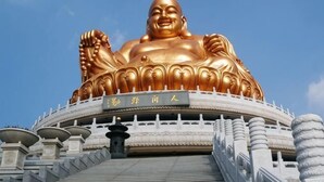 A large golden statue with a sign in front. - Ala Hotel (Ningbo)