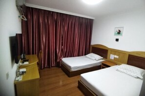 Une chambre d’hôtel avec deux lits, un bureau en bois, une chaise, une télévision et un rideau.
