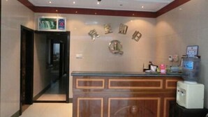 A reception desk with a wooden panel design, a digital screen, and a wall-mounted sign with Chinese characters. - Ala Hotel (Ningbo)