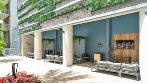 Un espace extérieur abrité, doté de fauteuils confortables et d’une structure en bois où sont disposées des bouteilles.